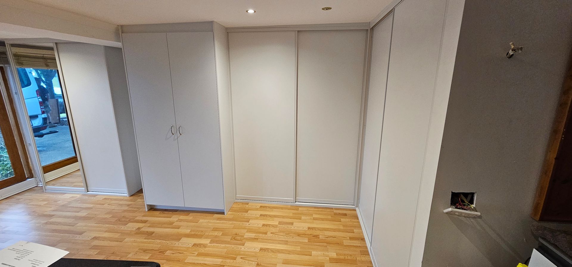 A room with a lot of white cabinets and a wooden floor.
