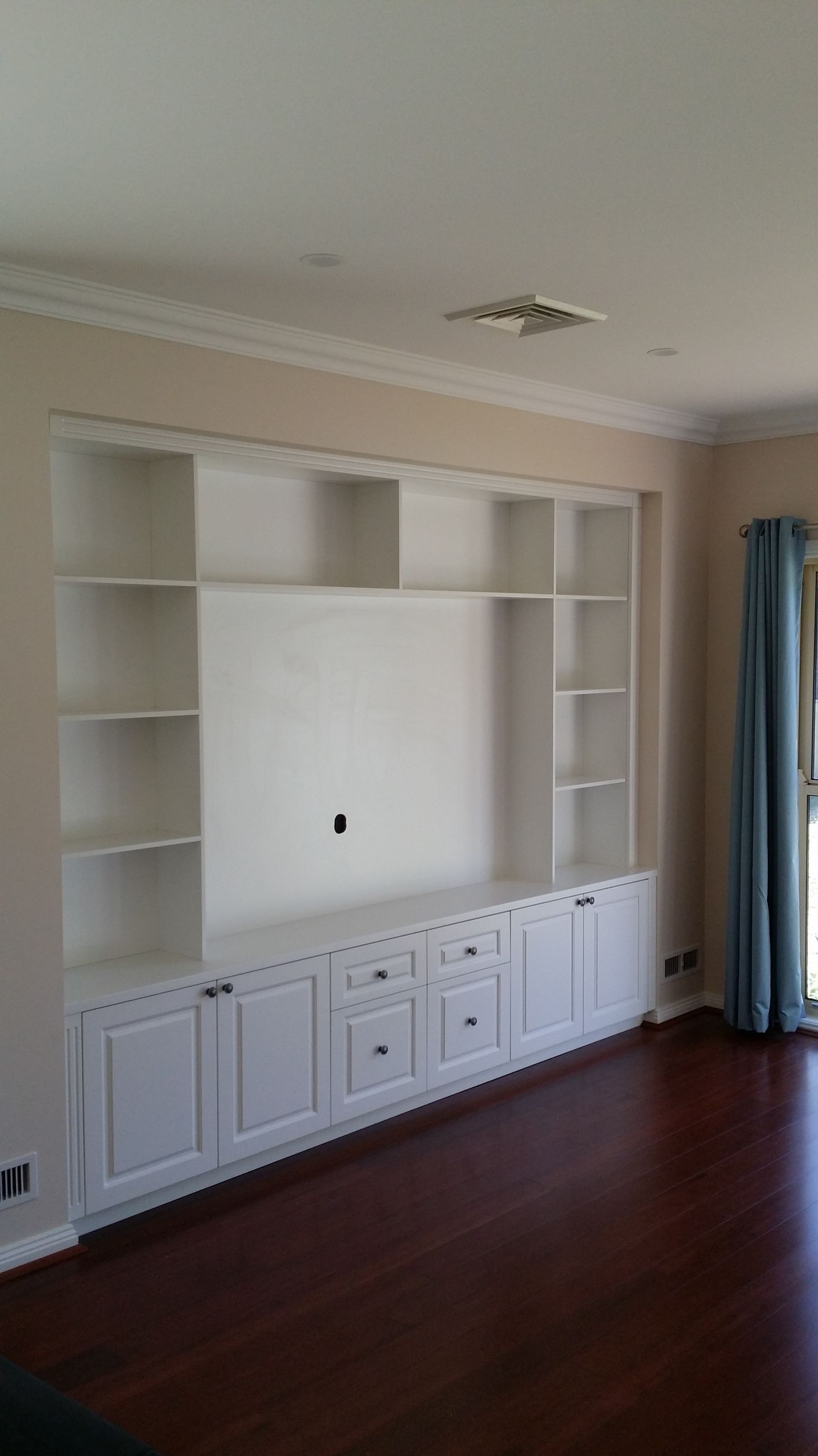 A living room with a large entertainment center and lots of shelves