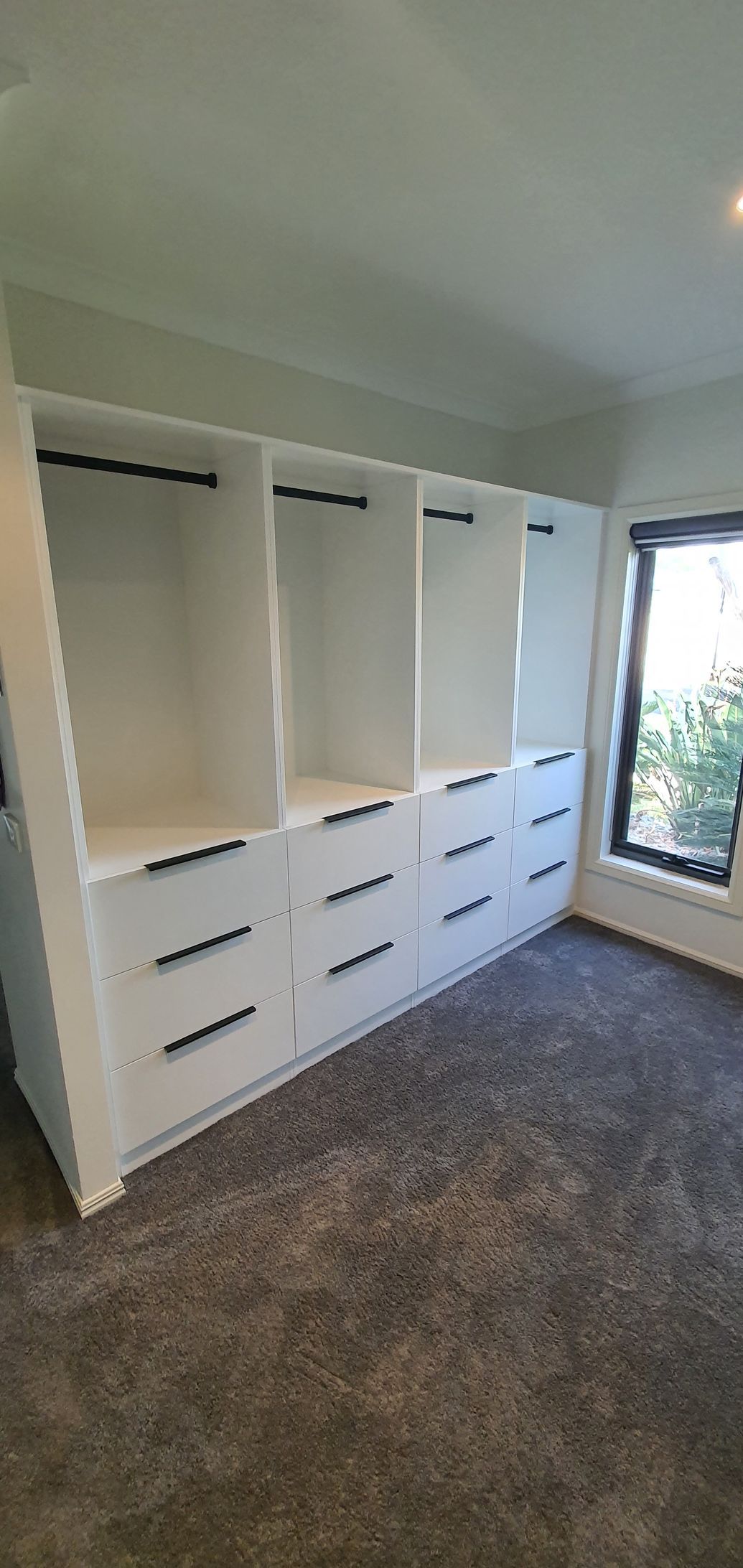 A large closet with lots of drawers and shelves in a room with a window.