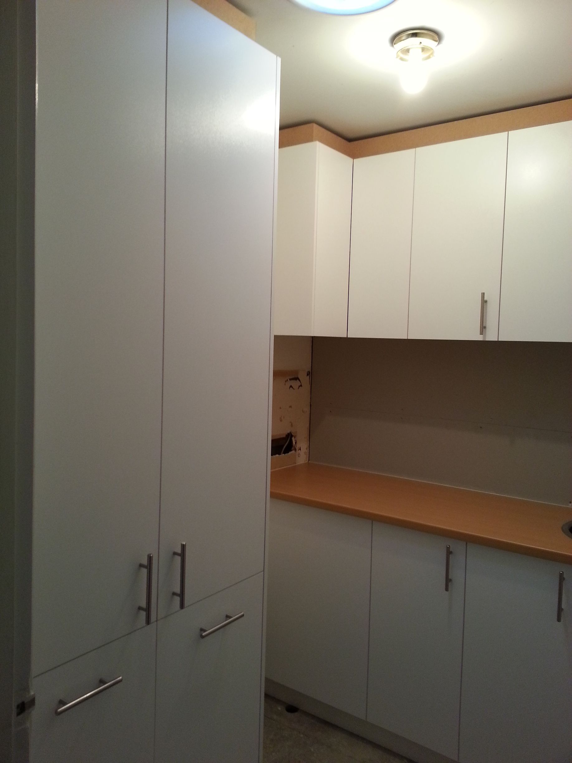 A kitchen with white cabinets and wooden counter tops