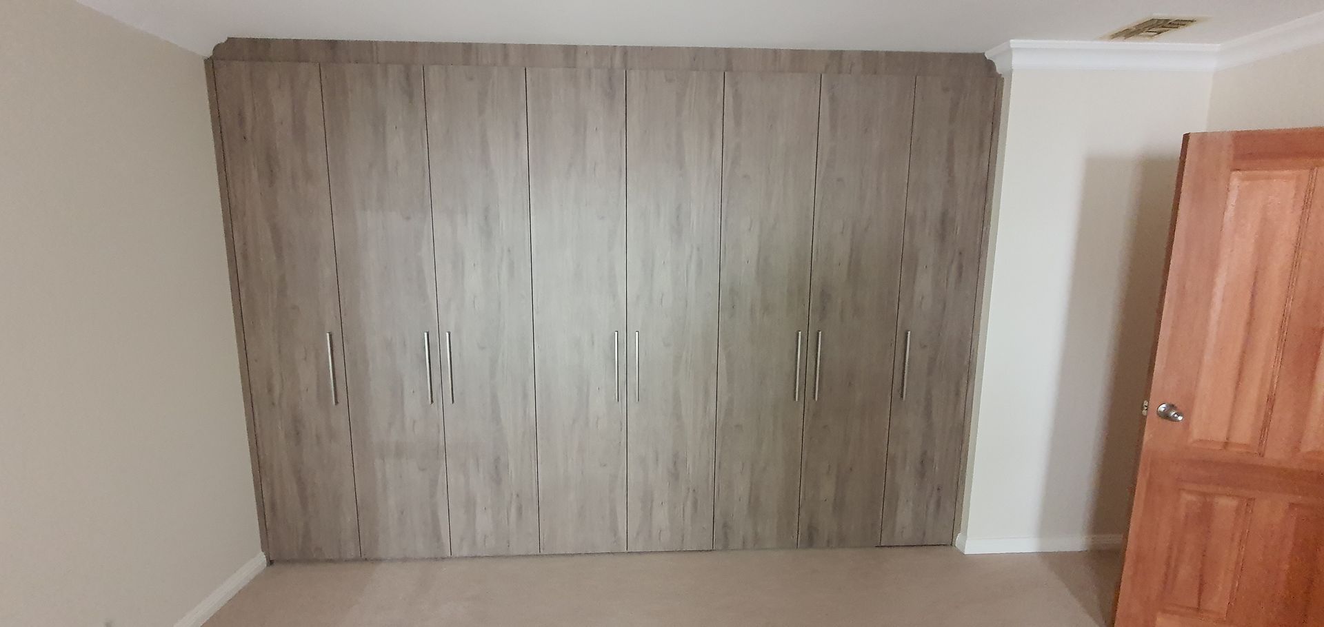 A bedroom with a large wardrobe and a door.