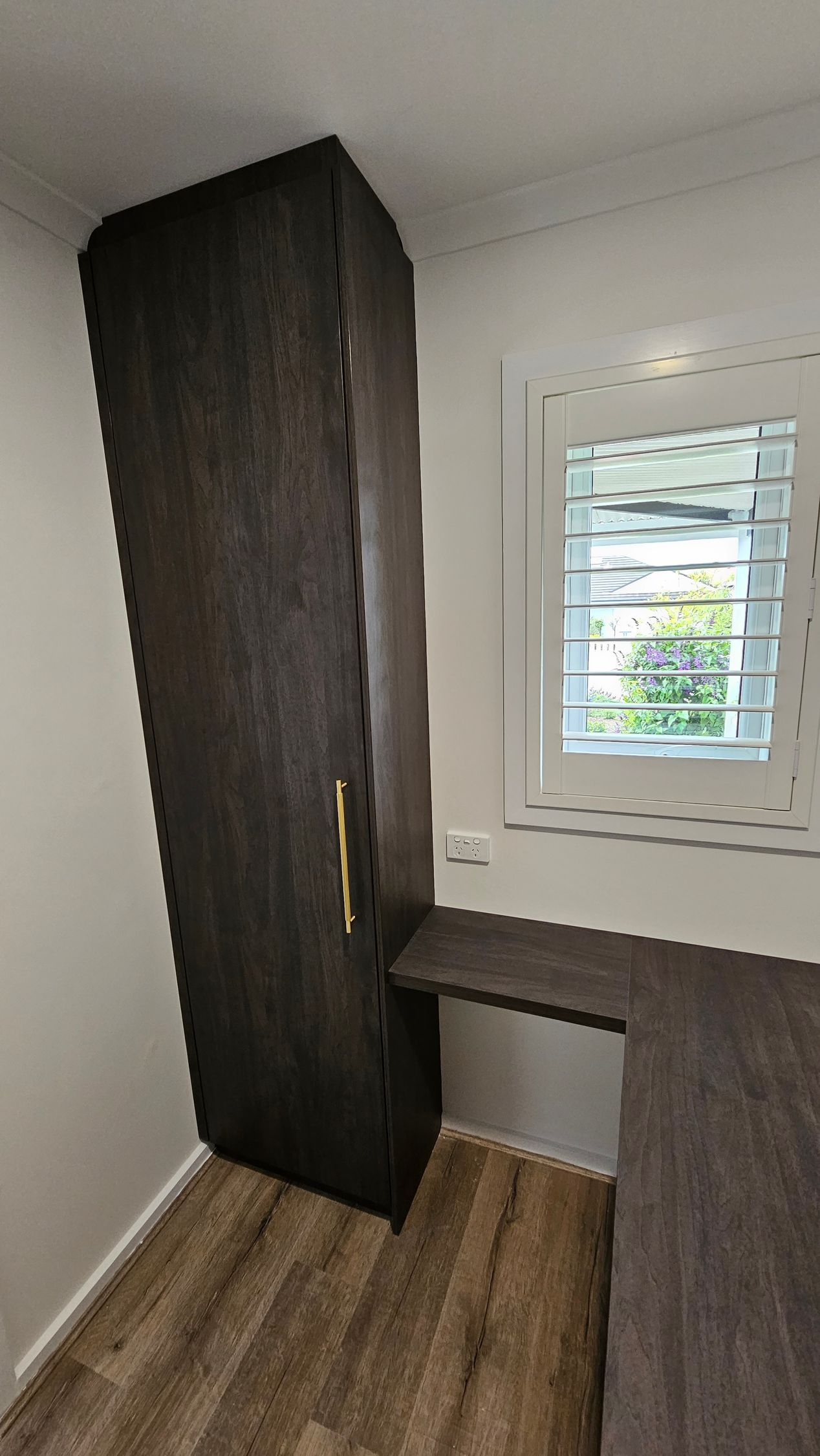 A room with a window , a desk , and a wardrobe.