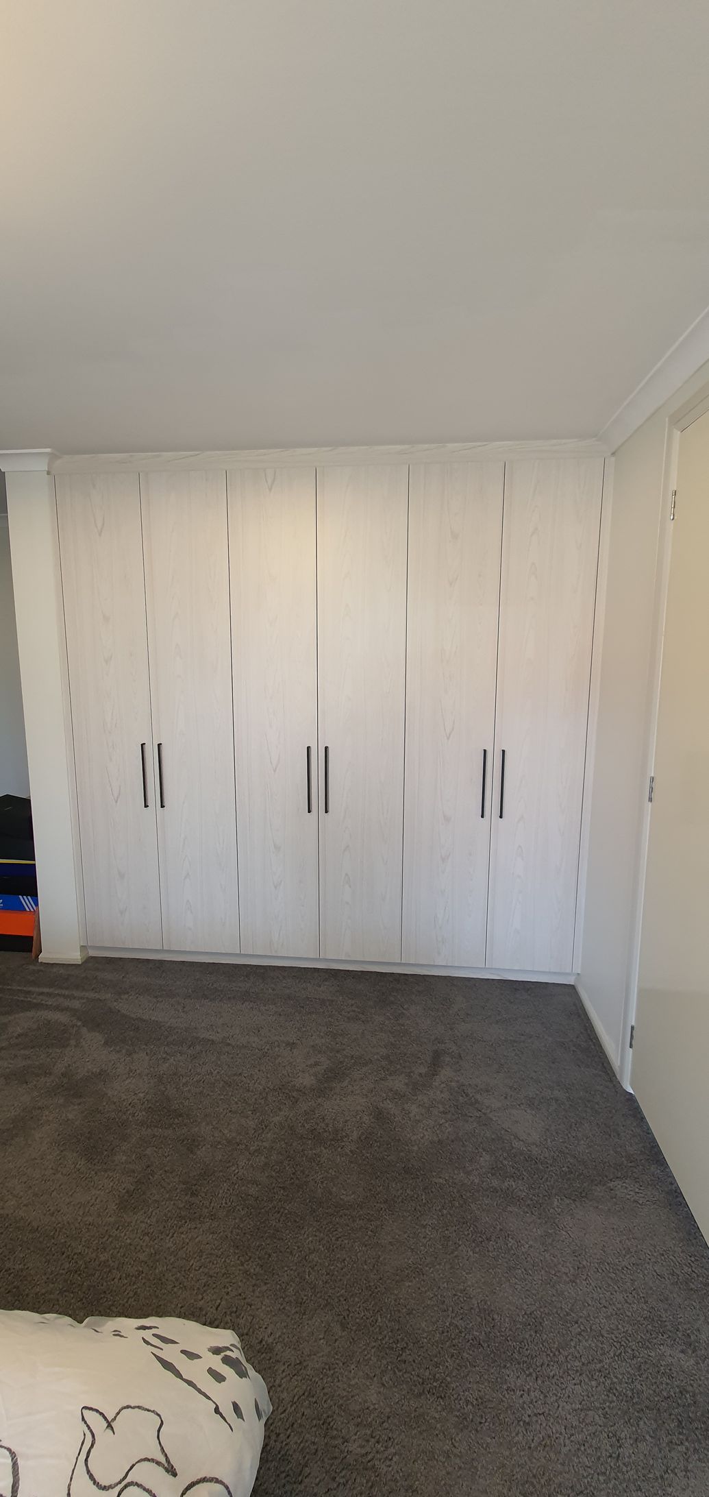 A bedroom with a bed and a large wardrobe.