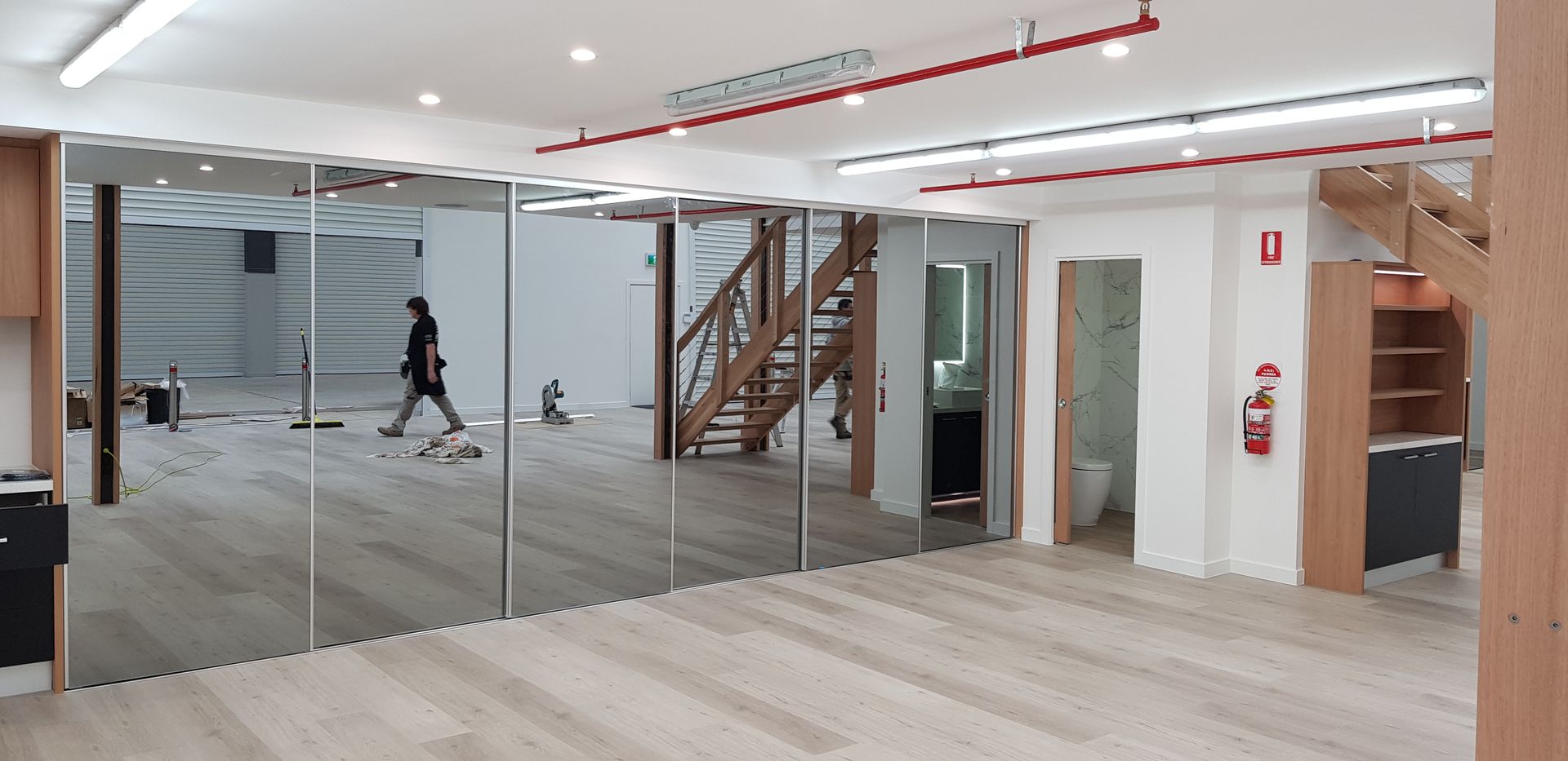 A room with a lot of mirrors on the wall and a staircase in the background.