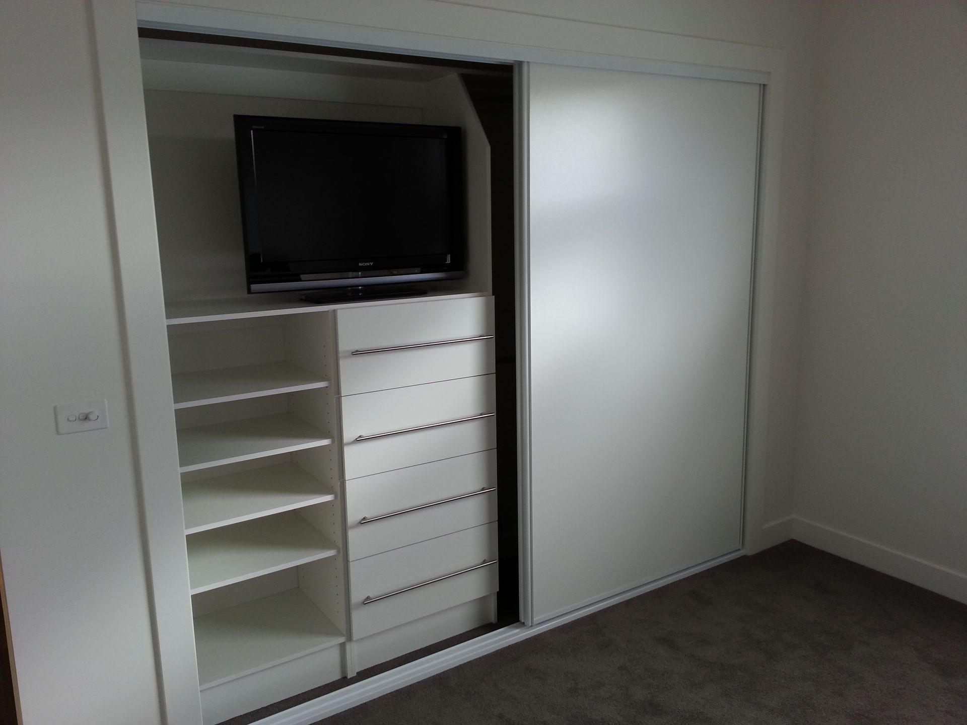A closet with sliding doors and a flat screen tv
