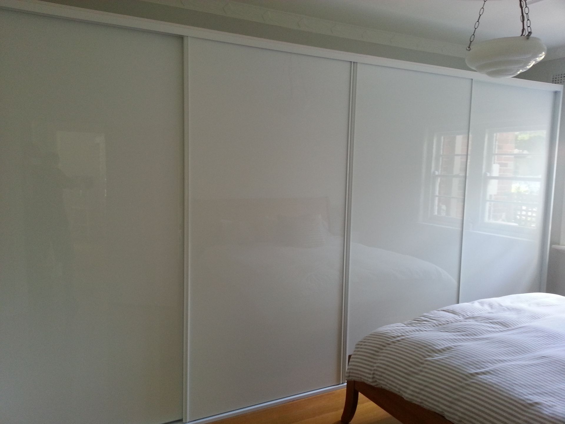 A bedroom with white sliding glass doors and a bed.