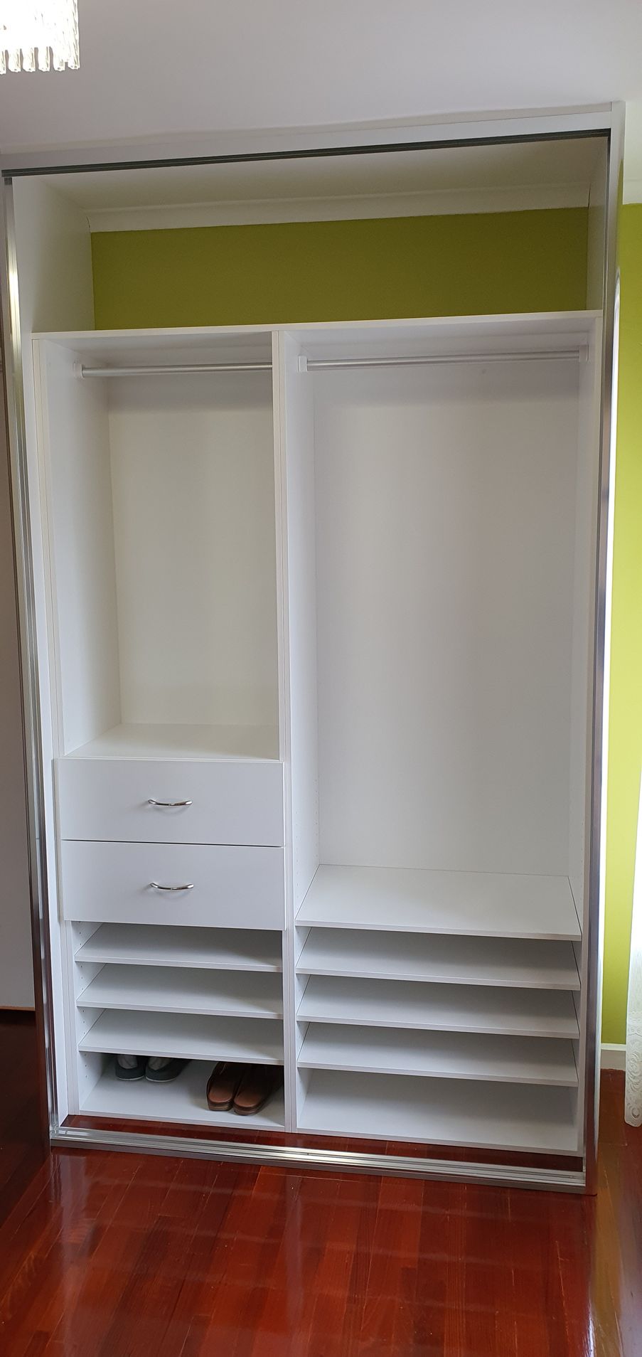 A large white wardrobe with lots of shelves and drawers in a room.