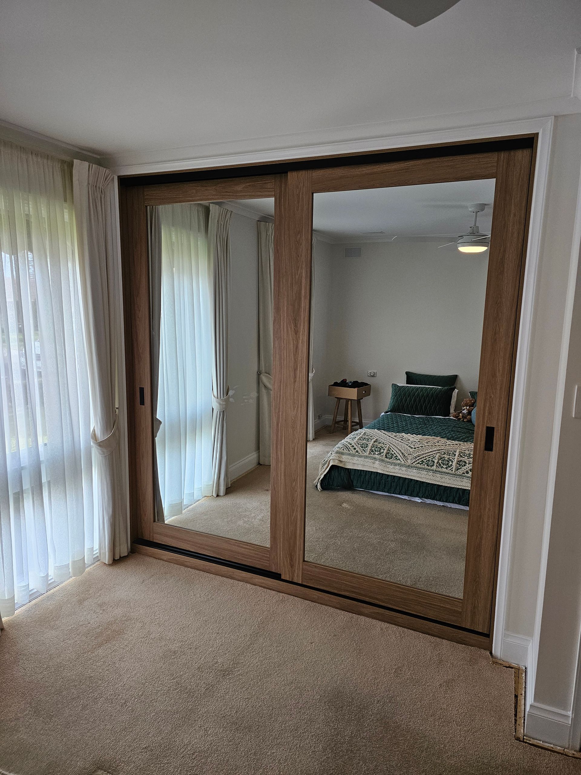 A bedroom with sliding glass doors and a large mirror.