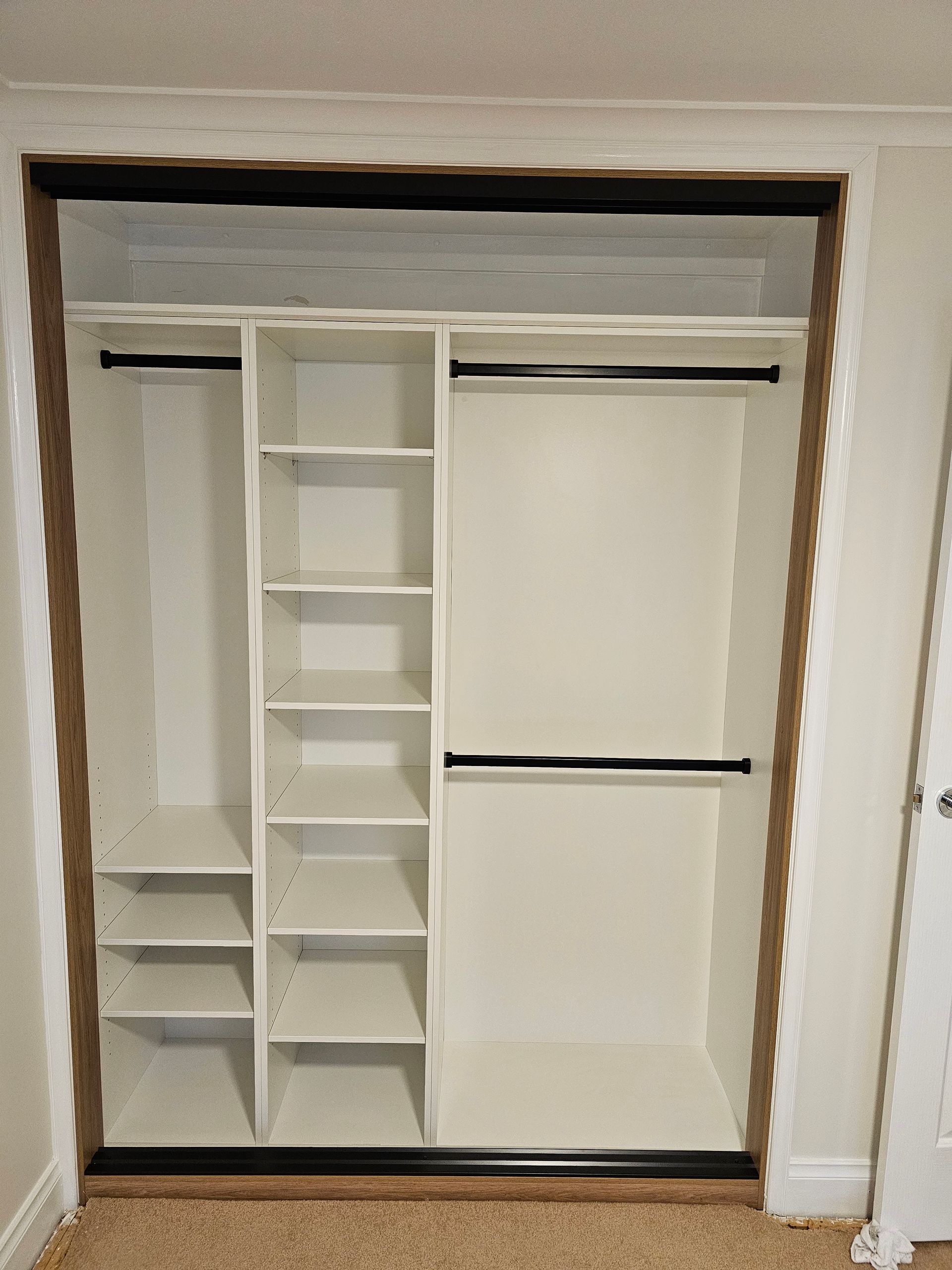 An empty closet with shelves and clothes racks in a room.