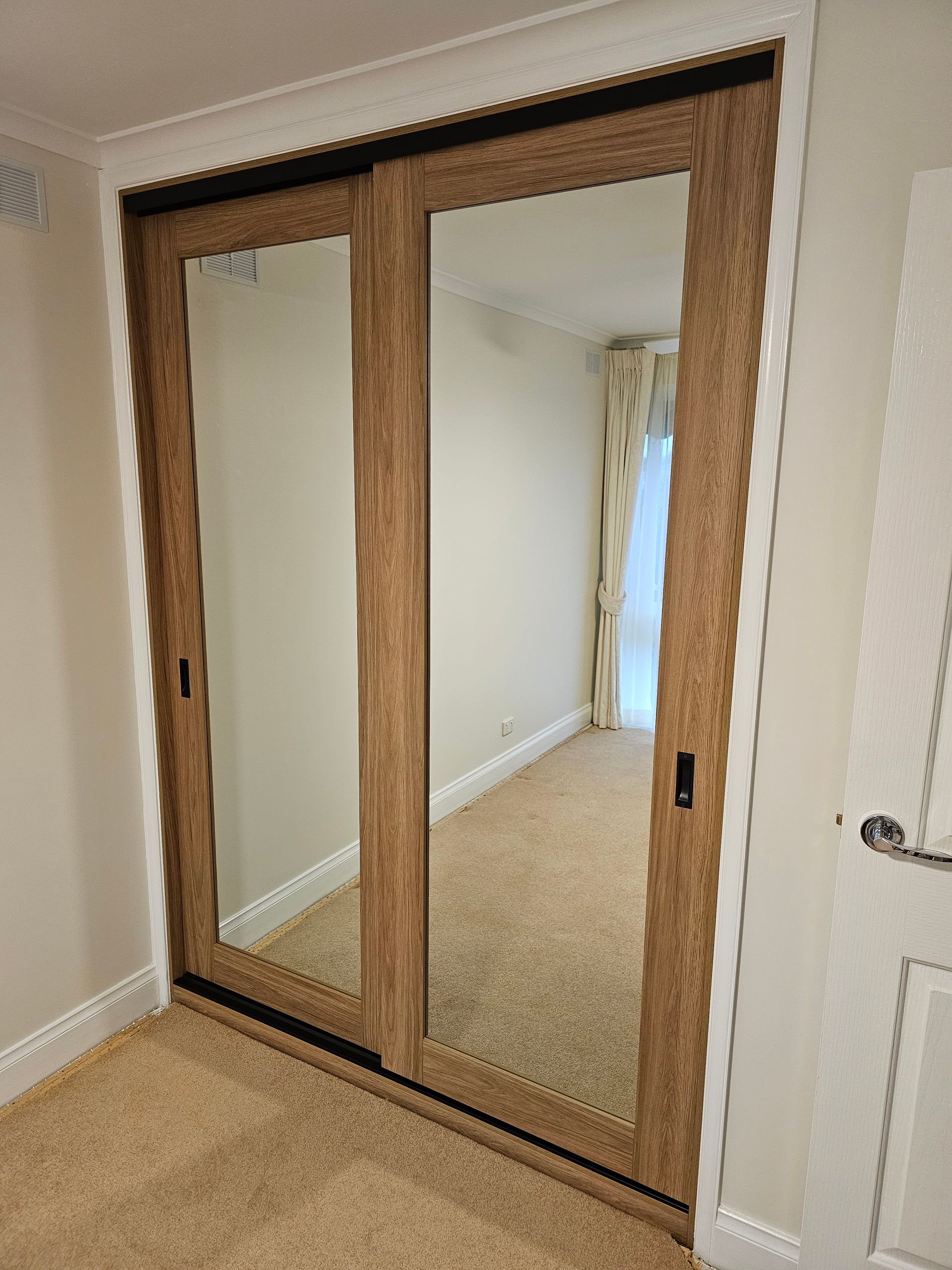 A sliding glass door with a mirror in a bedroom.