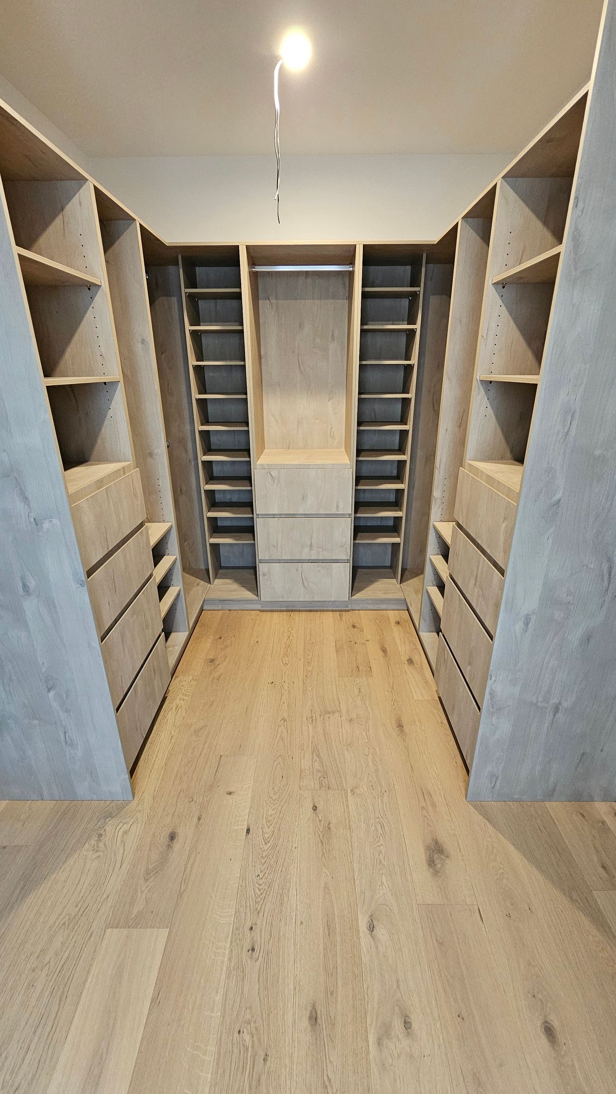 A walk in closet with lots of shelves and drawers.