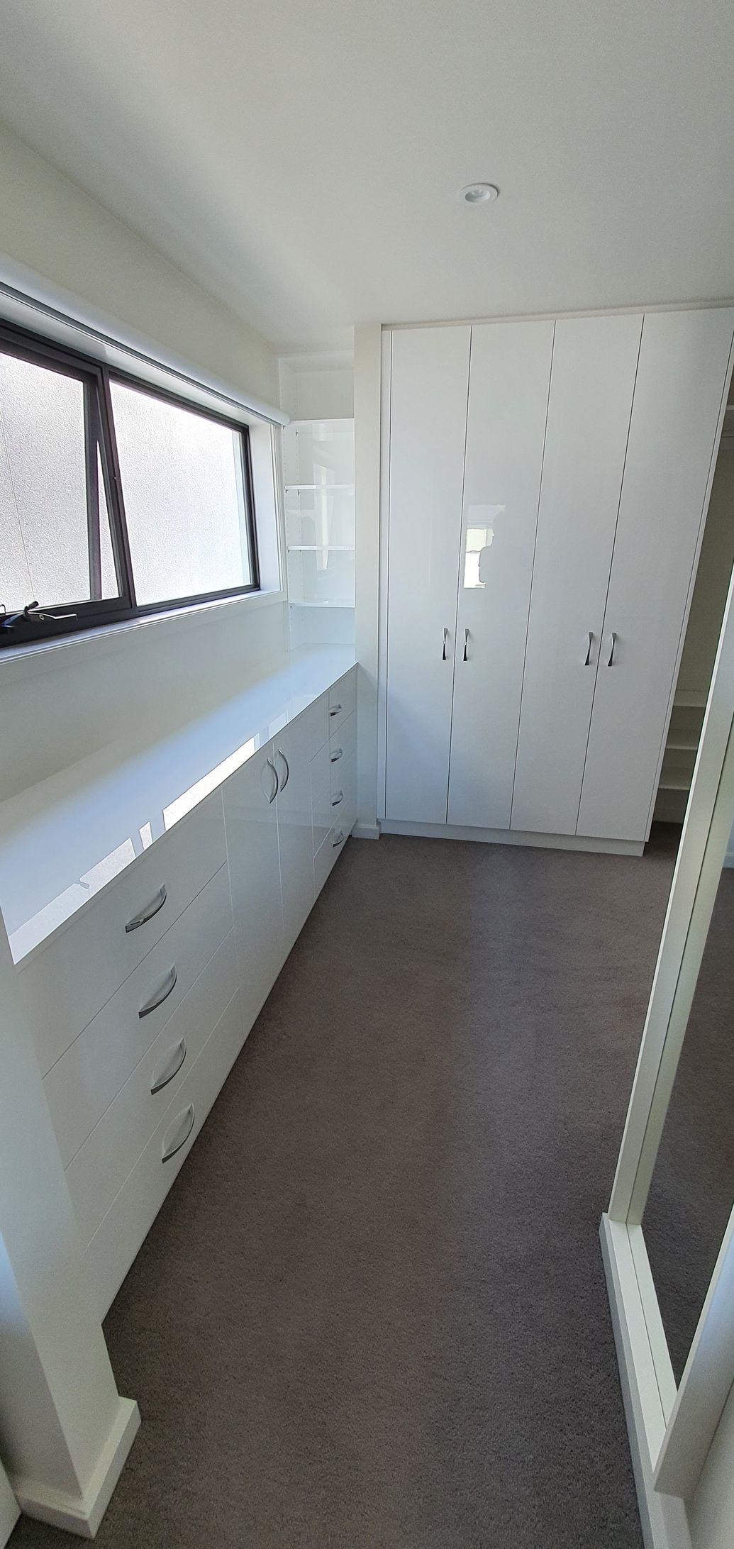 A large empty room with white cabinets and a window.