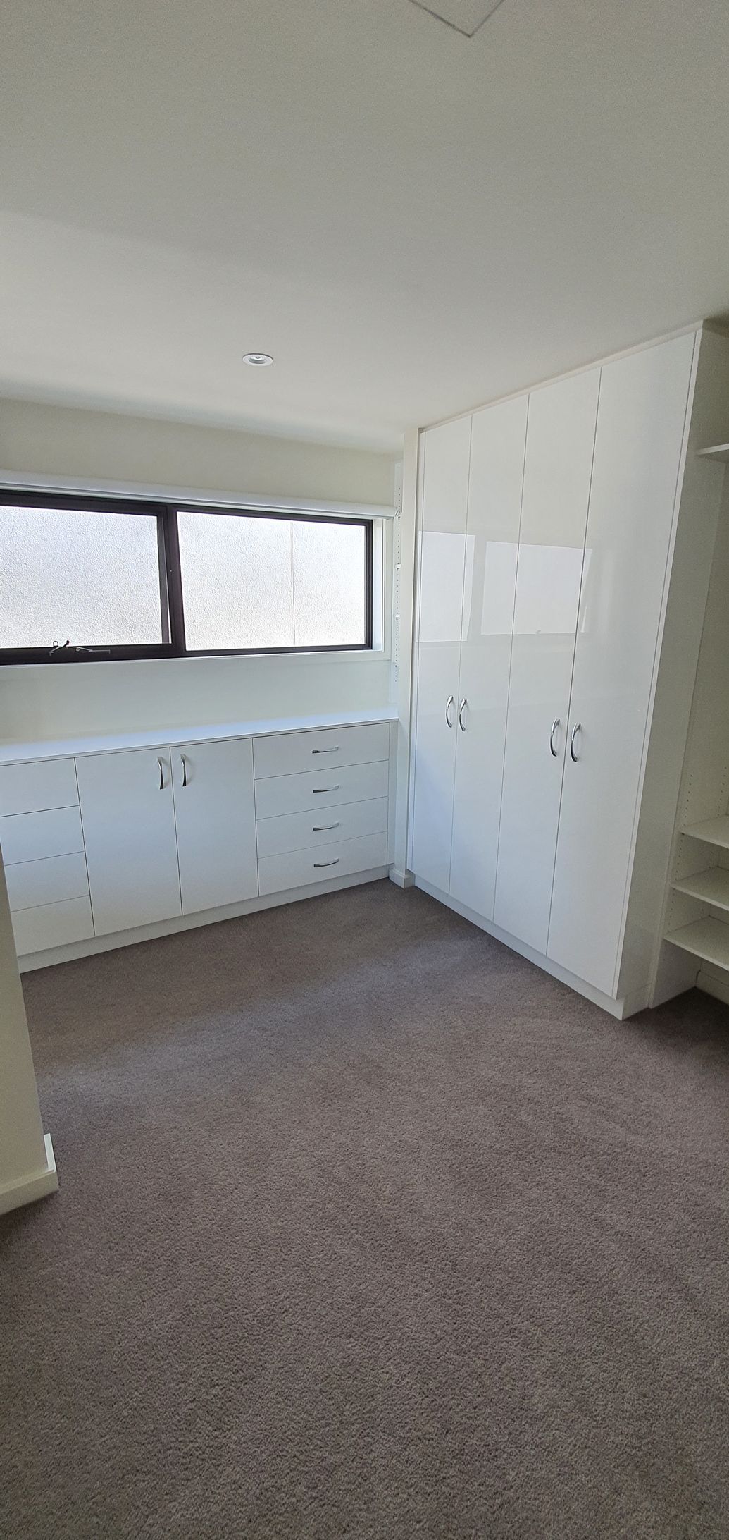 An empty room with a carpeted floor and a window.