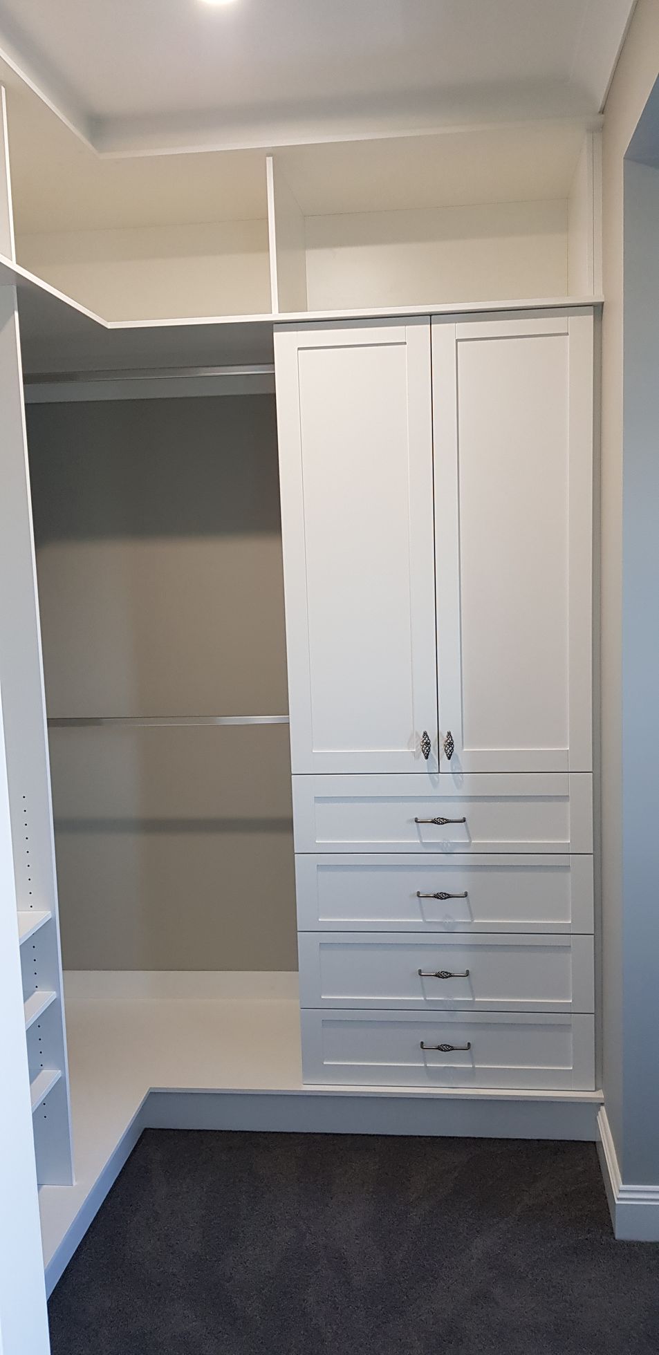A walk in closet with white cabinets and drawers in a bedroom.