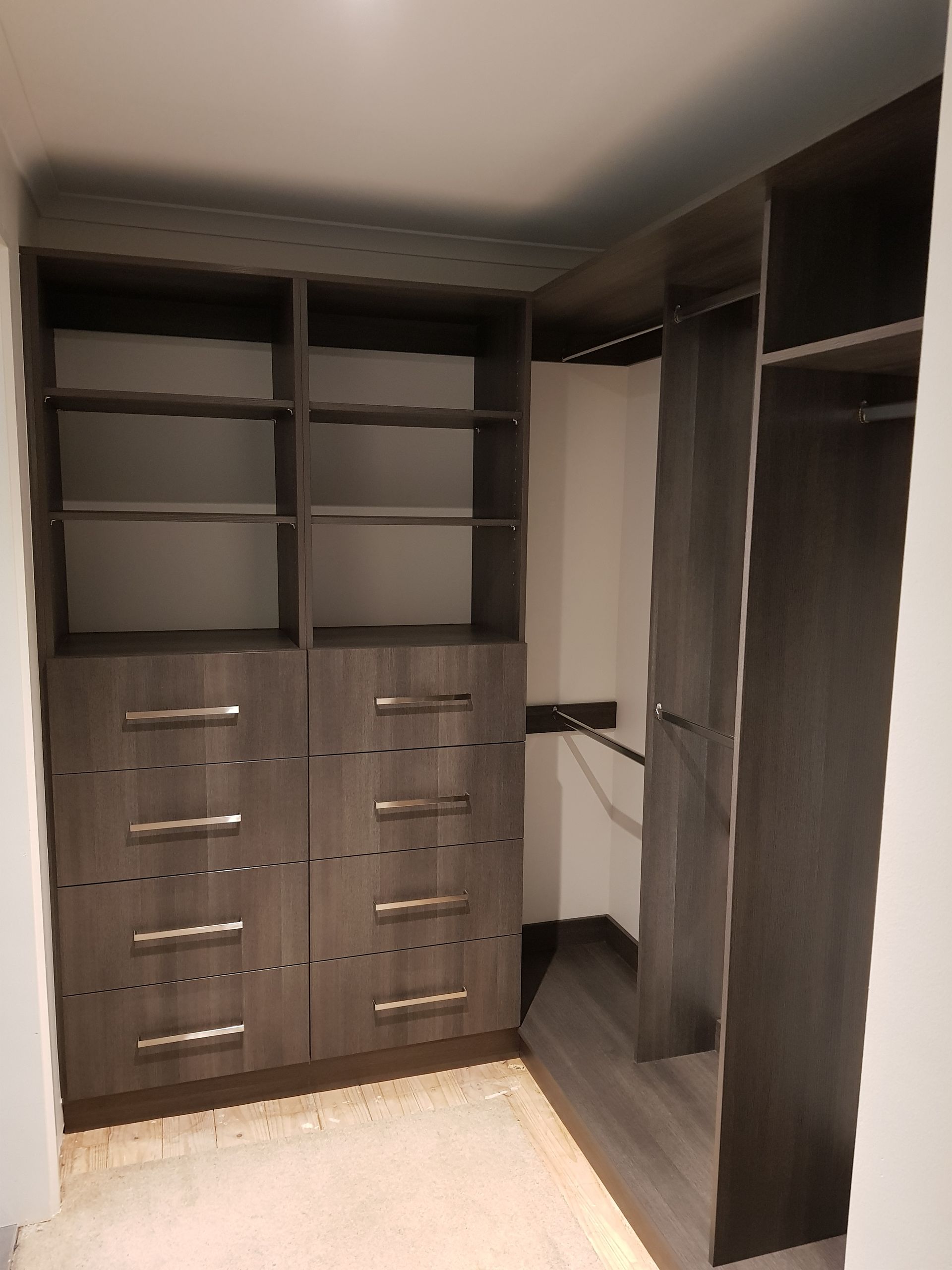 A walk in closet with lots of shelves and drawers