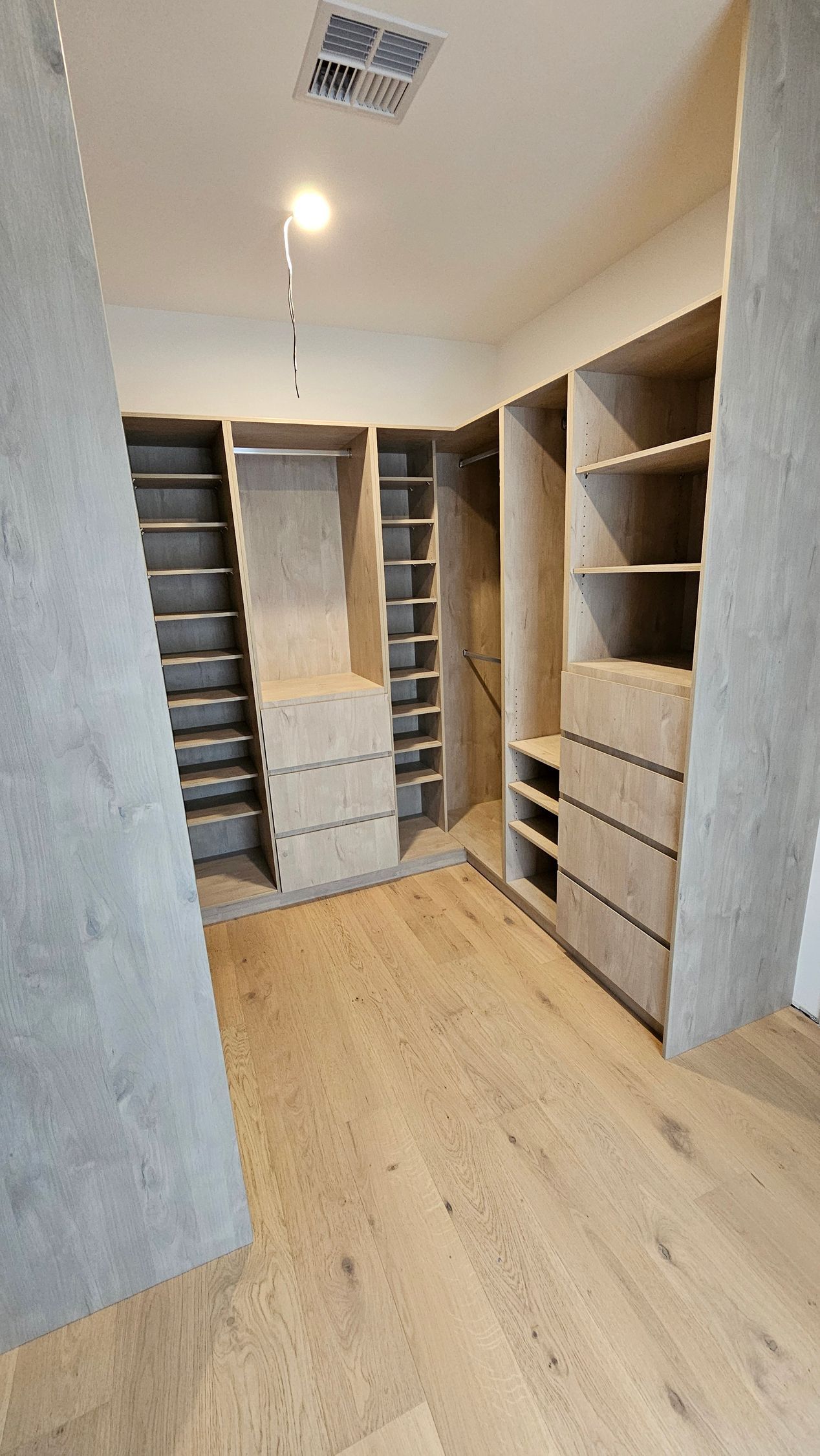 A walk in closet with lots of shelves and drawers.