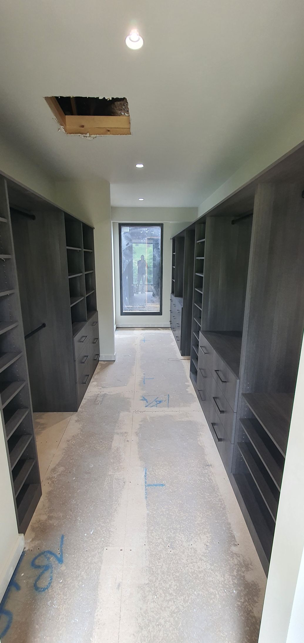 A long walk in closet with lots of shelves and drawers.