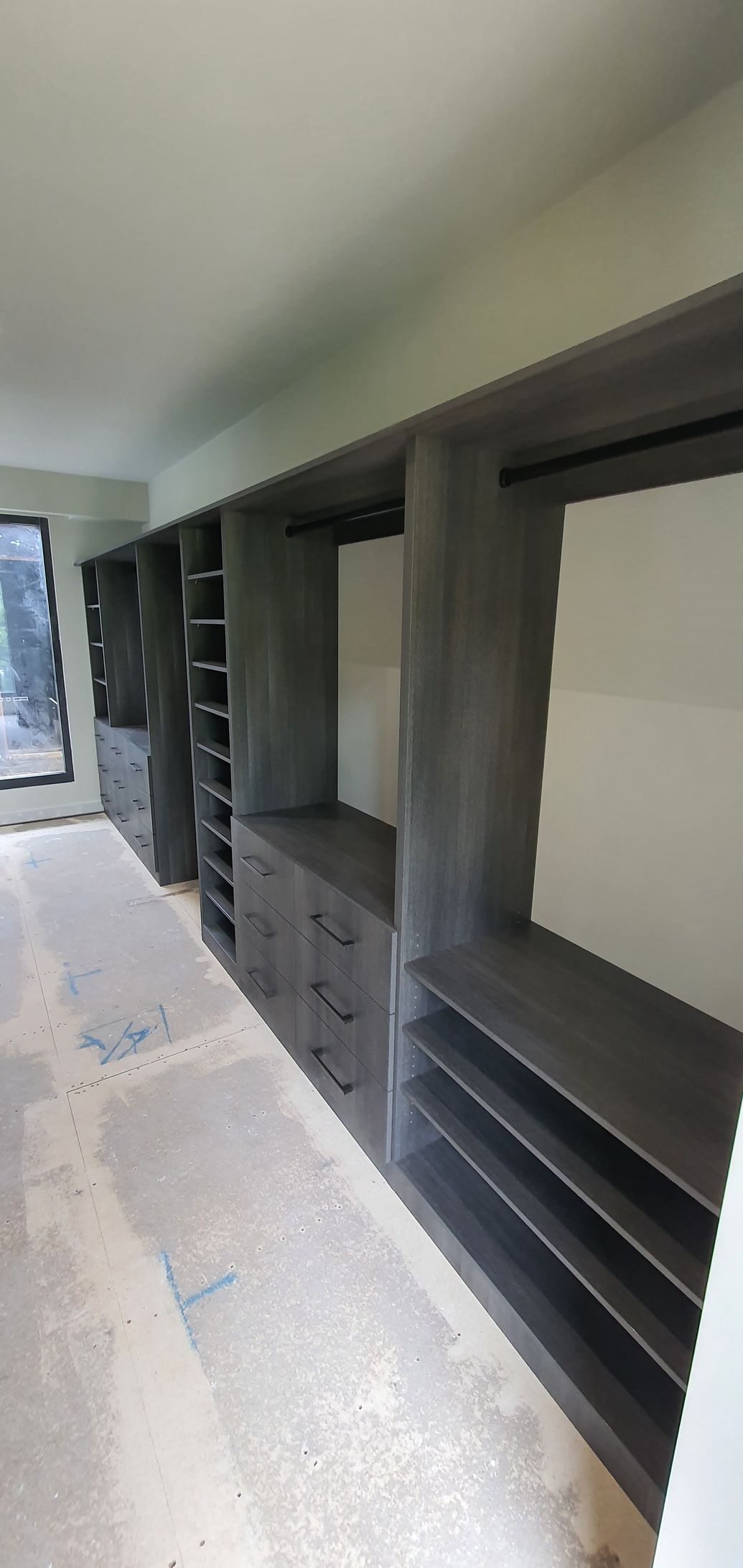A large walk in closet with lots of shelves and drawers.