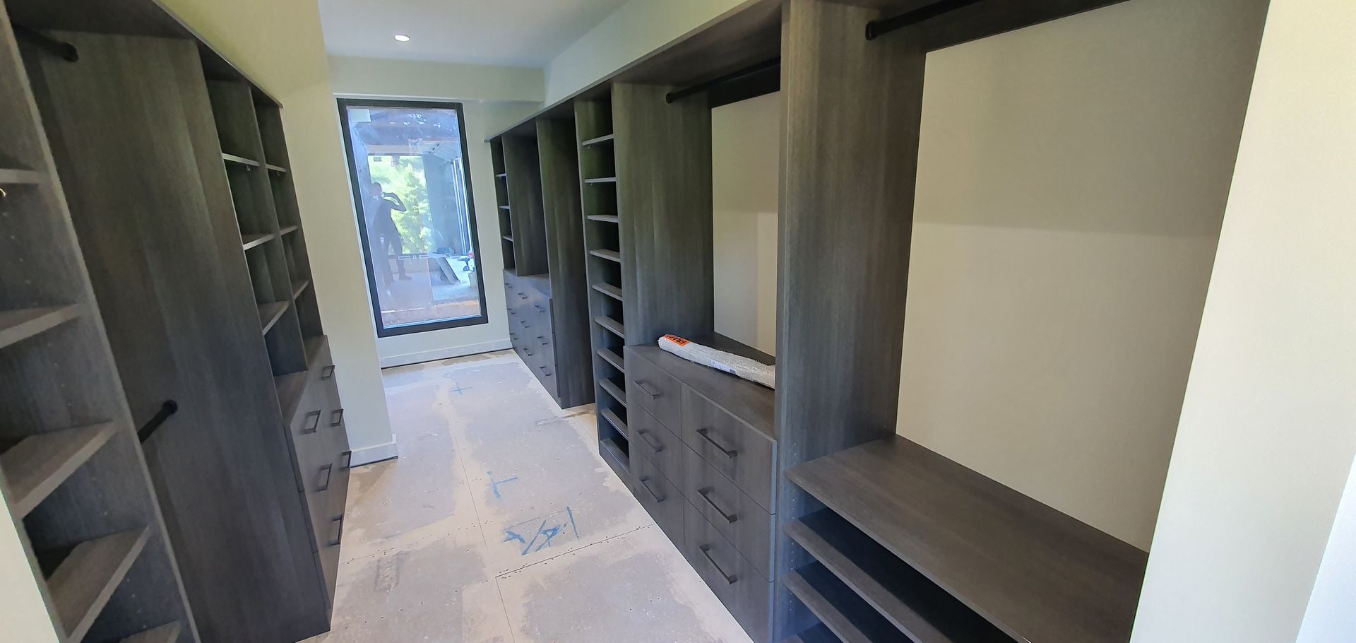 A walk in closet with lots of shelves and drawers in a house.