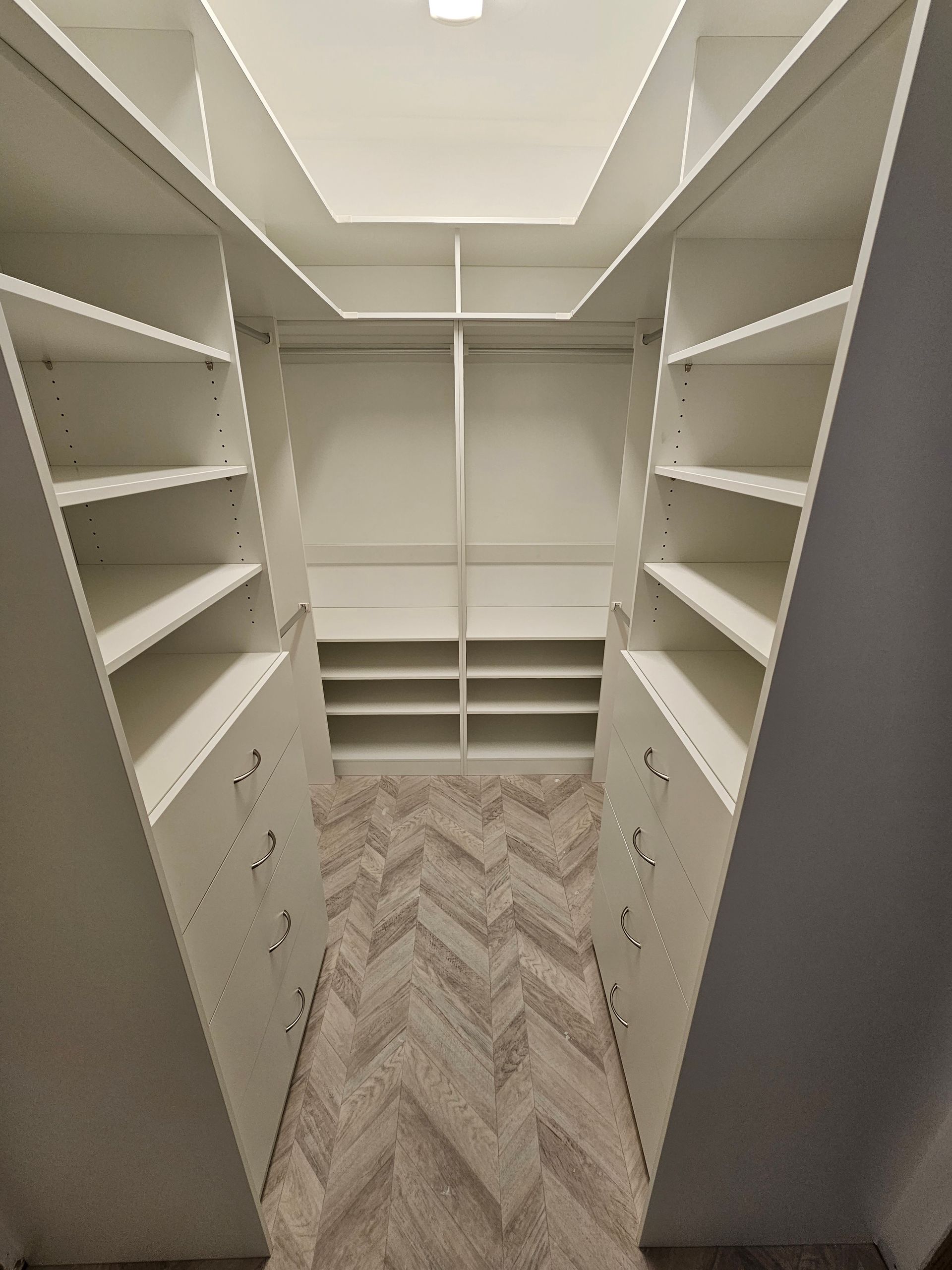 A walk in closet with lots of shelves and drawers.