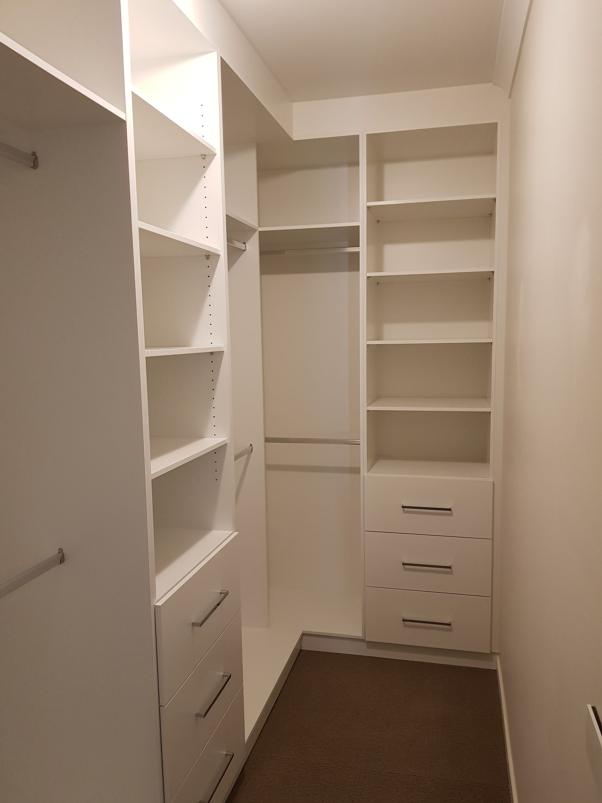 A walk in closet with lots of shelves and drawers.