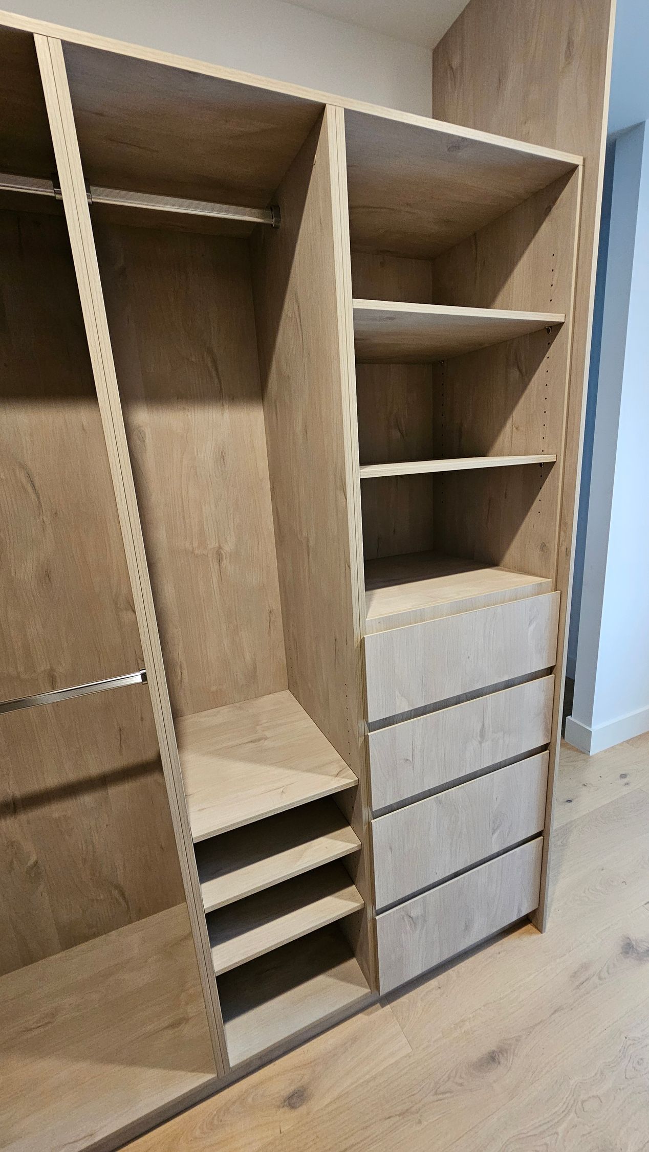 A walk in closet with wooden shelves and drawers.