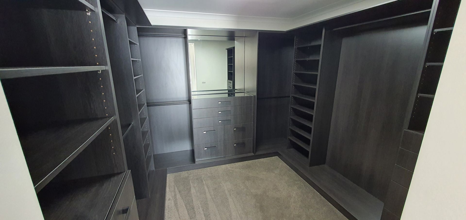 A walk in closet with lots of shelves and a mirror