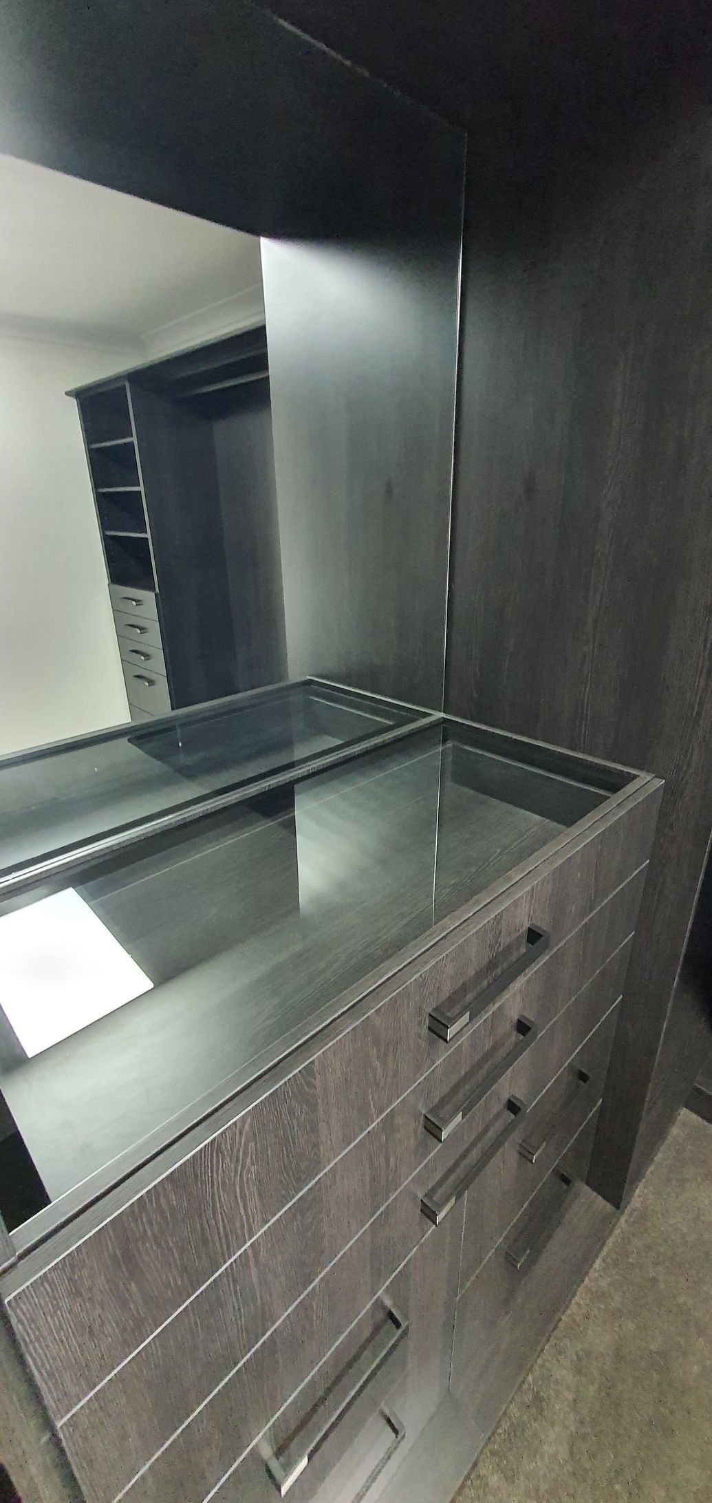 A walk in closet with a large mirror and drawers.