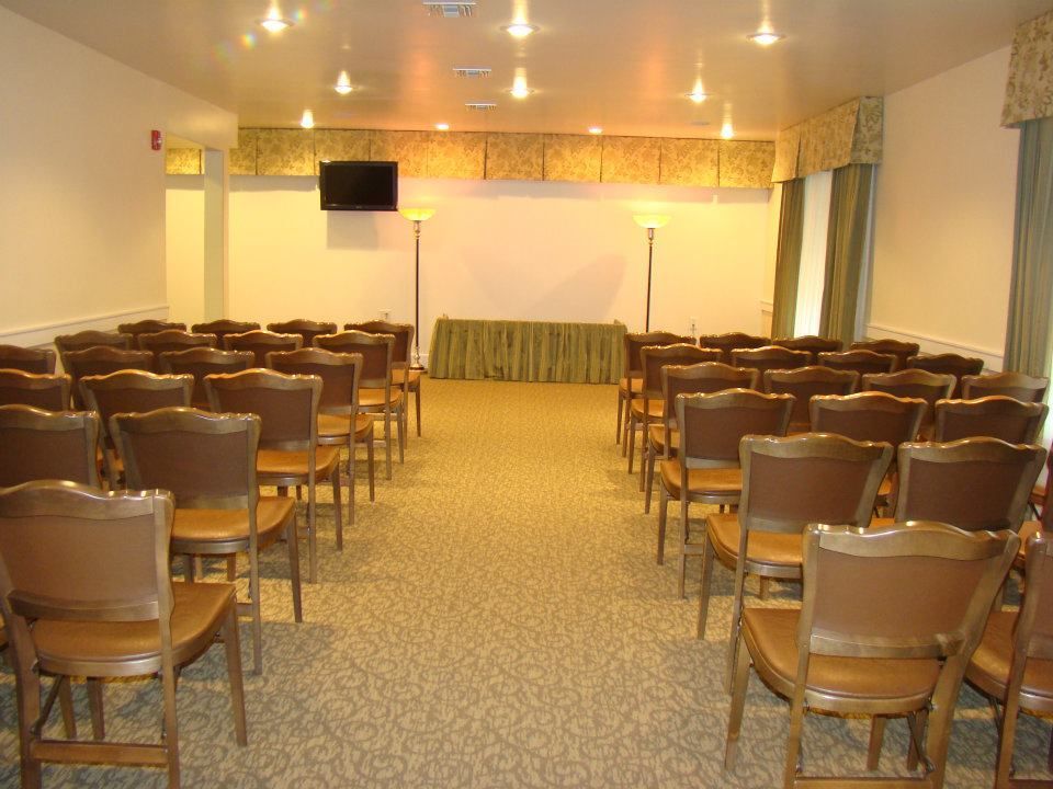 A room with rows of chairs and a tv on the wall