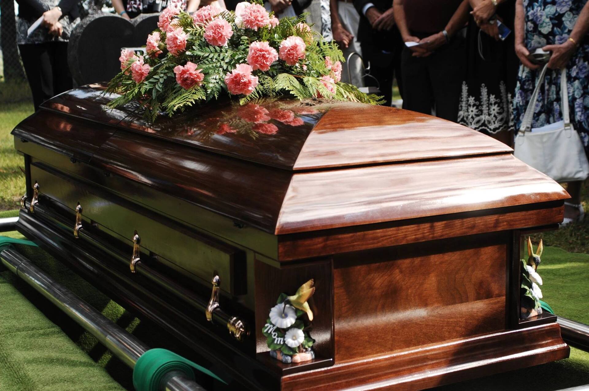 A wooden coffin with pink flowers on top of it