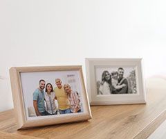 Three picture frames are sitting on a wooden table.
