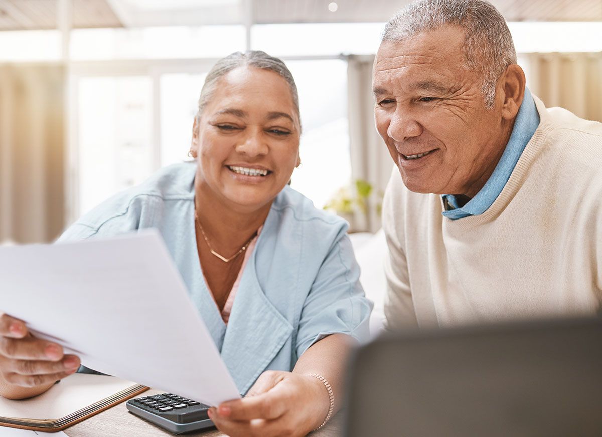 A man and a woman are sitting at a table looking at a piece of paper and a calculator.