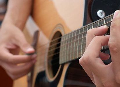 A close up of a person playing an acoustic guitar