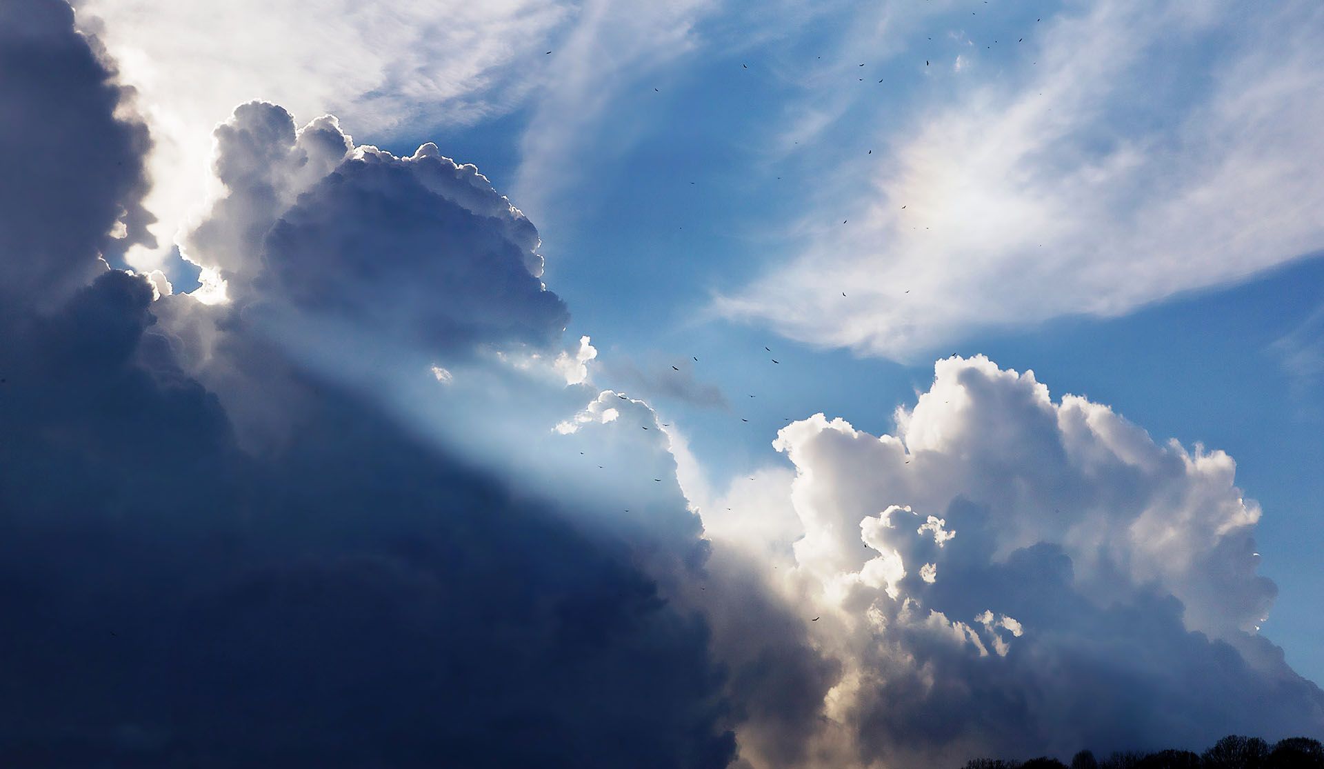 The sun is shining through the clouds in the sky