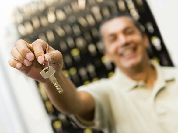 A man is holding a key in front of a display of keys.