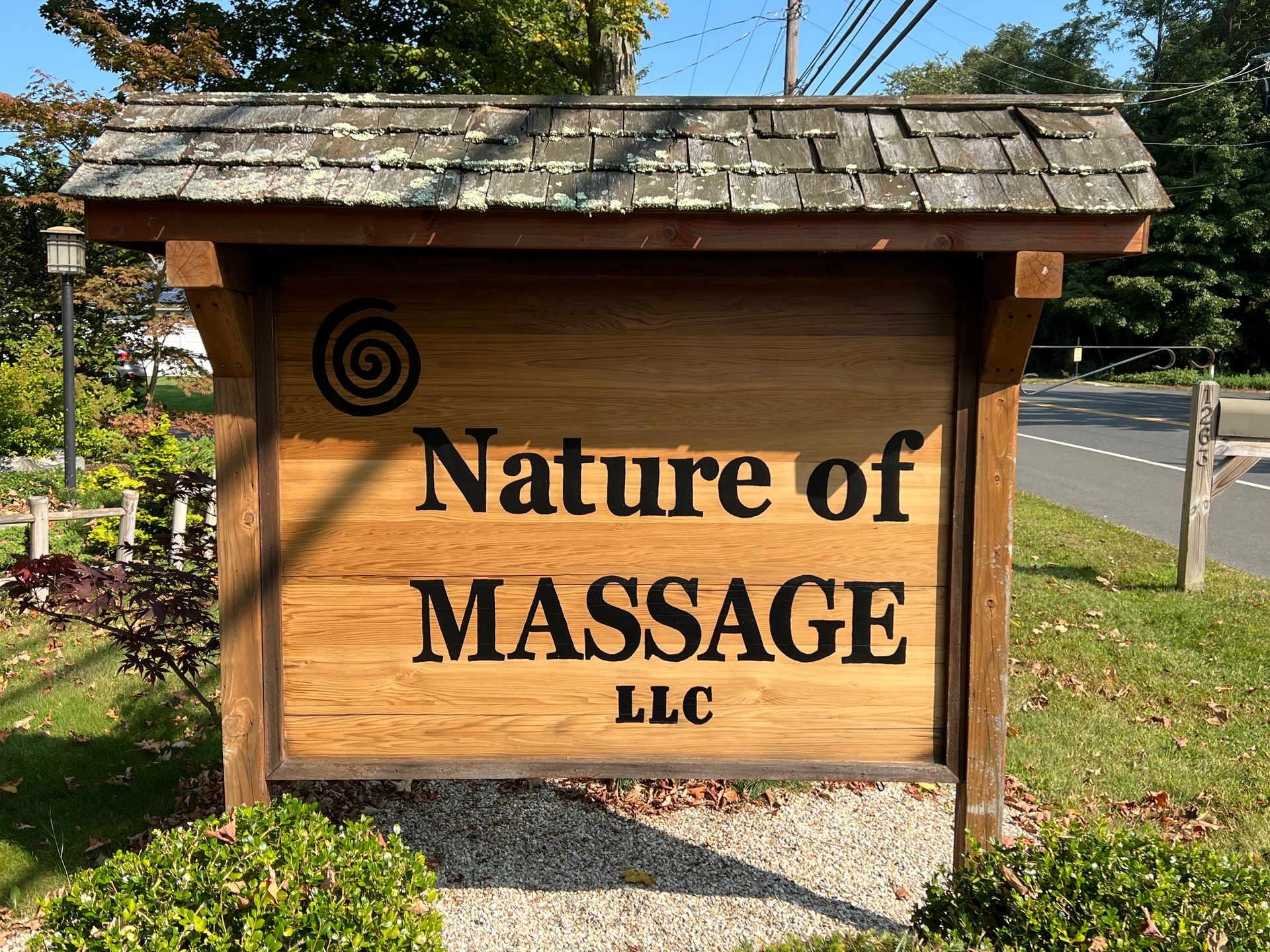 A wooden sign for Nature of Massage LLC