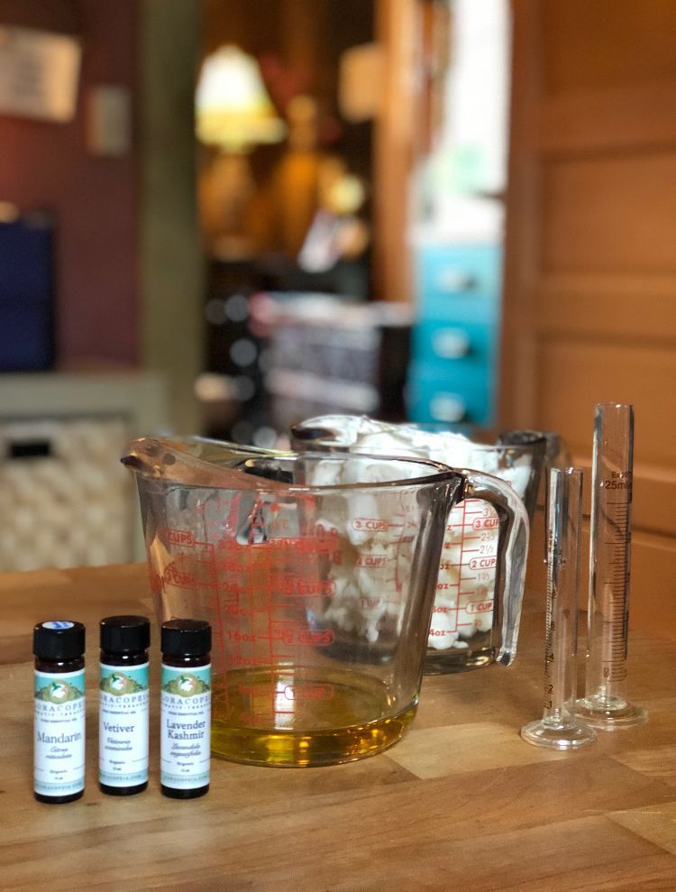 Three bottles of essential oils next to a measuring cup