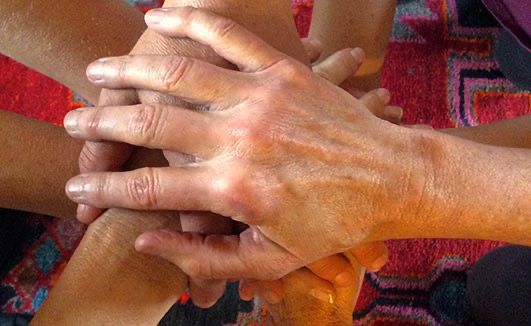 A group of people are stacking their hands on top of each other.