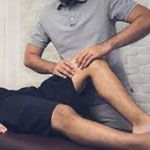 A man is giving a woman a massage on her leg.