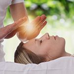 A woman is getting a reiki treatment on her face.