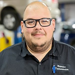 A man wearing glasses and a black shirt is smiling for the camera.