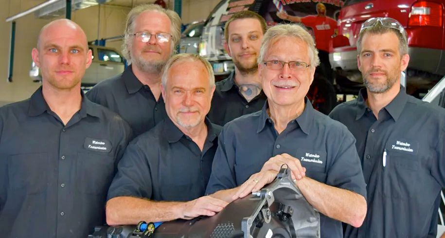 A group of men are posing for a picture in a garage.