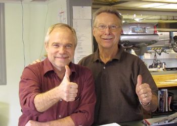 Two men are posing for a picture and one is giving a thumbs up