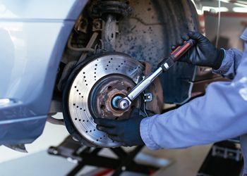 A man is fixing a brake disc on a car with a wrench.