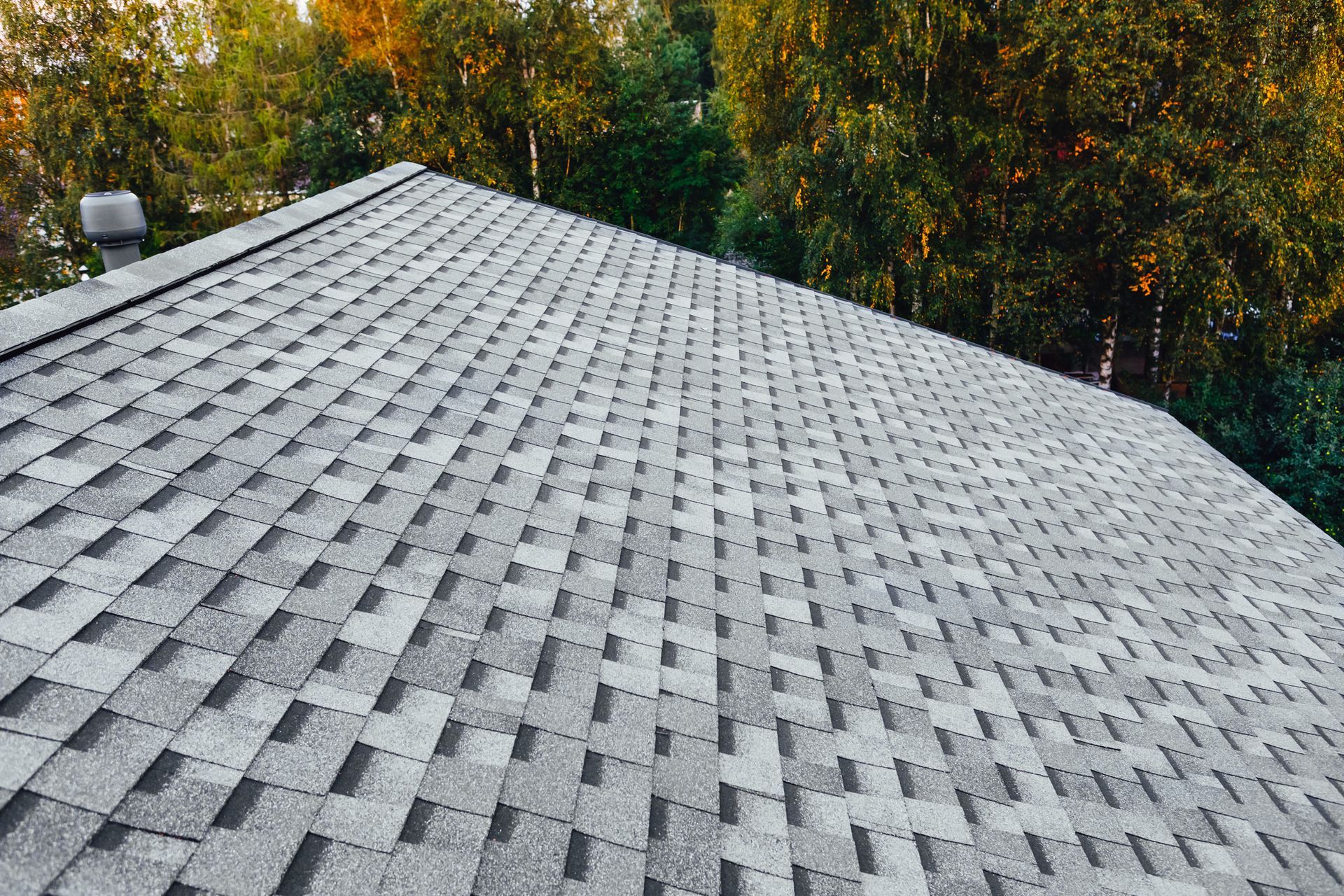 A roof with a lot of shingles on it is surrounded by trees.
