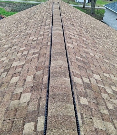 Two construction workers are working on the roof of a house.