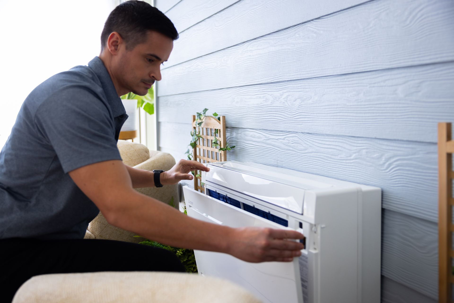 Pfluke Home Services technician installing an air conditioner on an exterior wall.