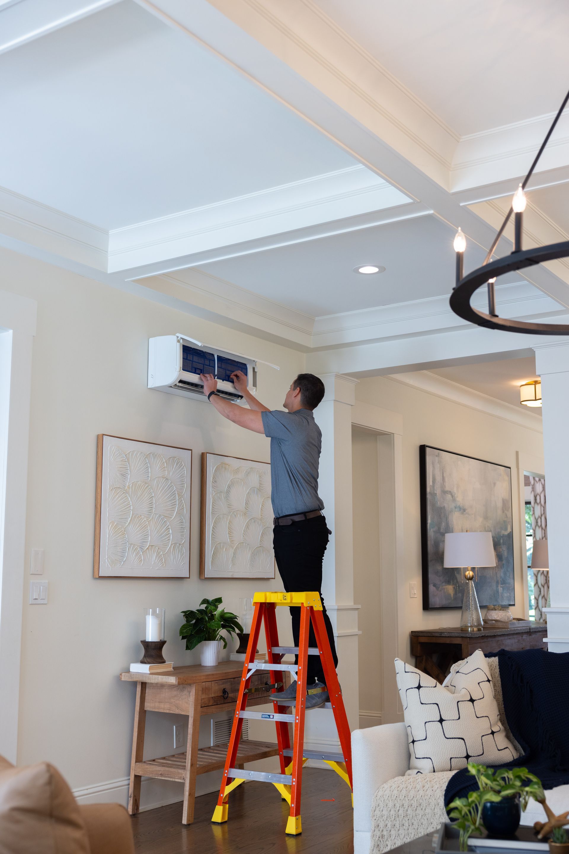 Person on a ladder installing an AC unit inside a home.
