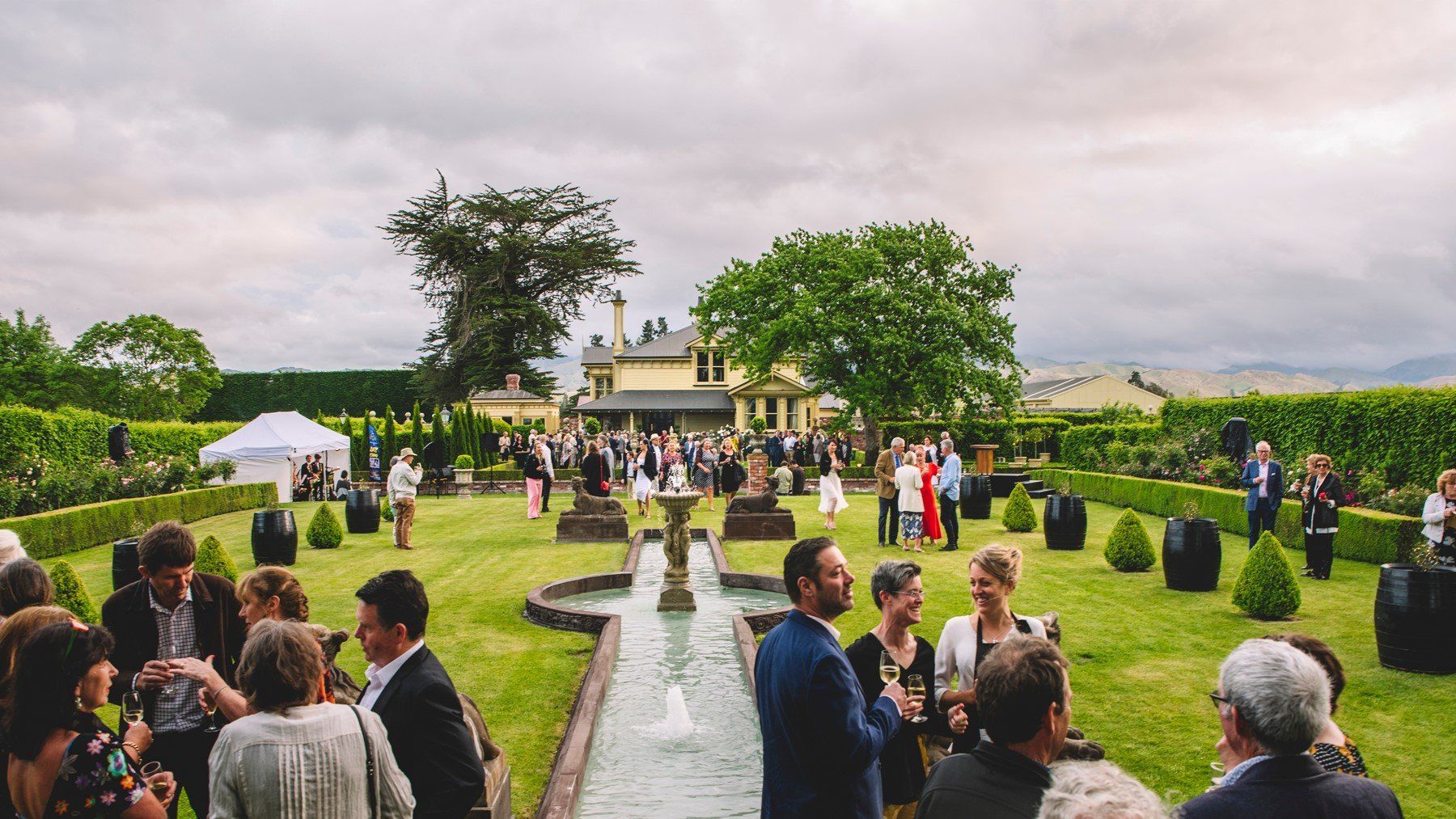 A group of people are standing around a fountain in a garden.