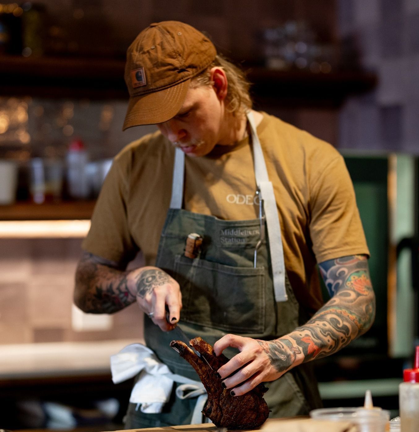 A man wearing an apron and a hat is cooking